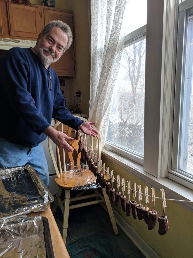 Dave presents a line of chocolate-covered bananas hanging on a clothesline in his house.