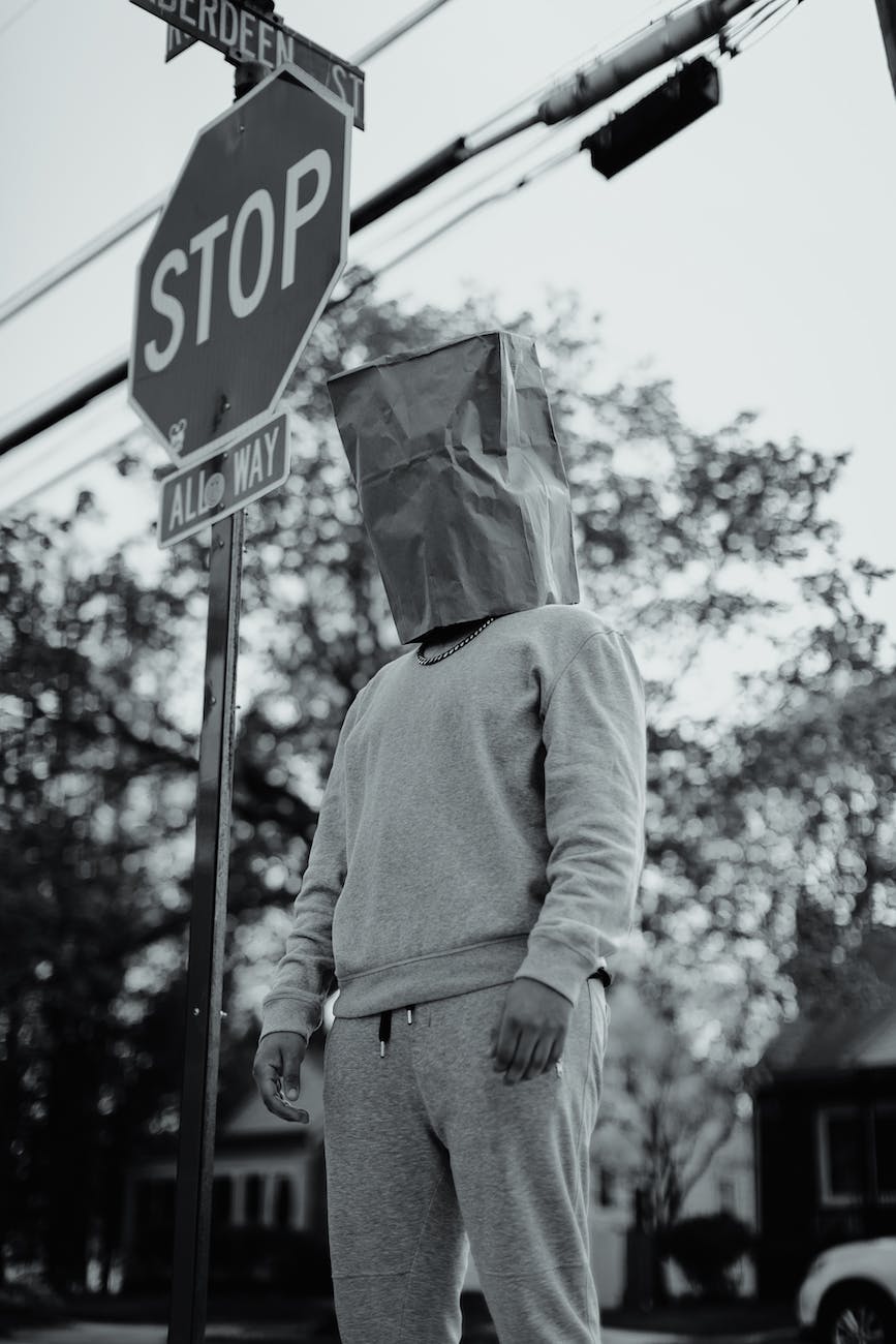 grayscale photography of man with paper bag on his head